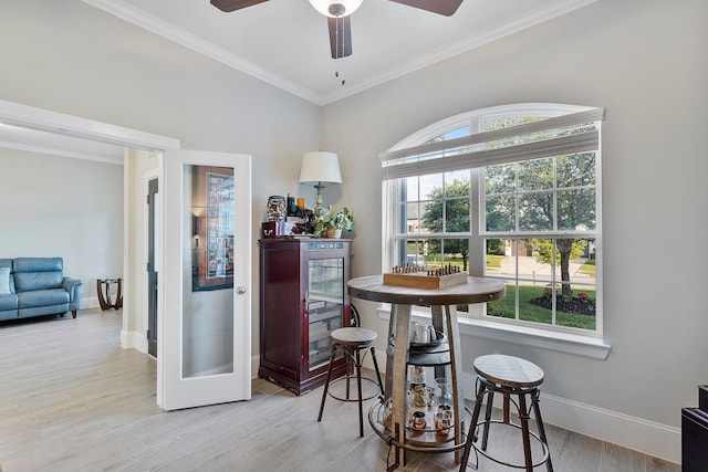 dining room featuring light wood finished floors, a ceiling fan, ornamental molding, and baseboards