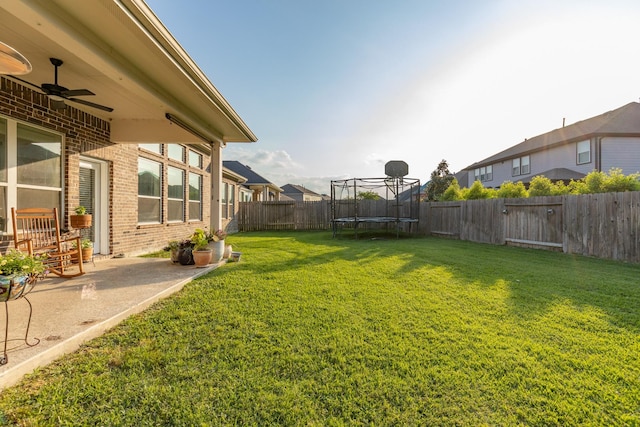 view of yard with a fenced backyard, a patio, ceiling fan, and a trampoline