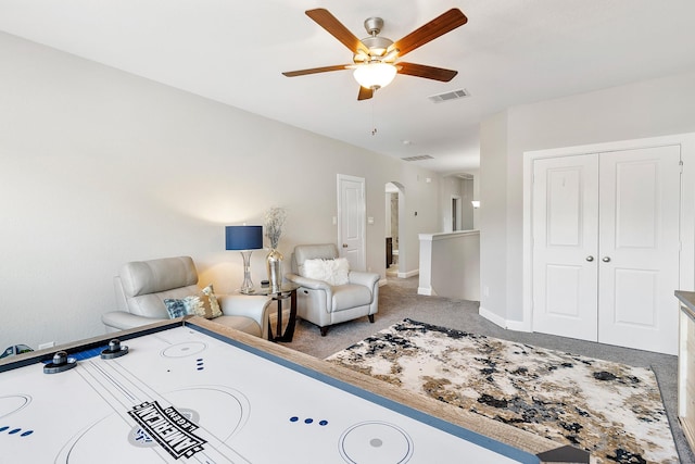 interior space with a ceiling fan, visible vents, carpet, baseboards, and arched walkways