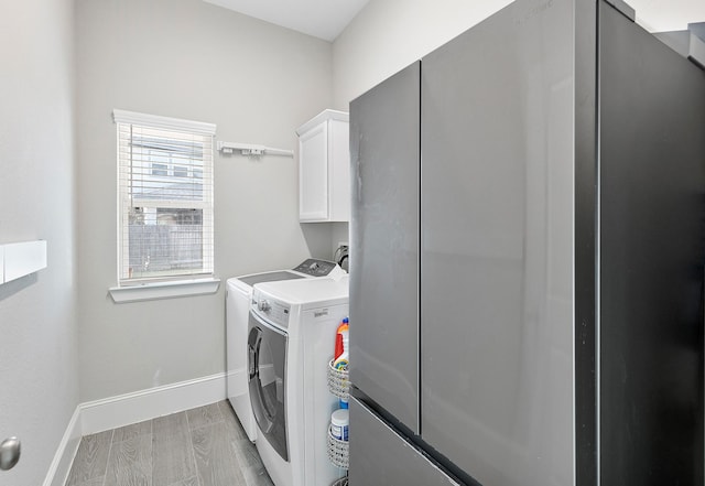 laundry area featuring independent washer and dryer, cabinet space, and baseboards
