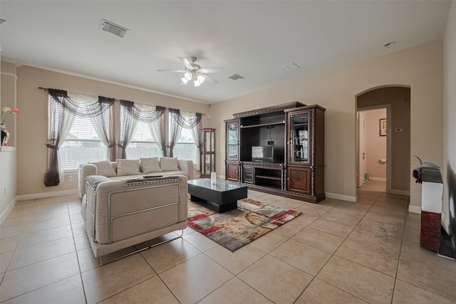 living room featuring visible vents, a ceiling fan, arched walkways, and light tile patterned floors