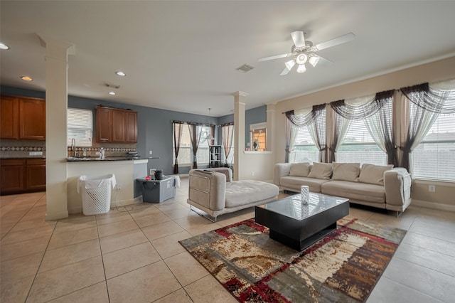 living area with light tile patterned floors, a ceiling fan, ornate columns, and visible vents