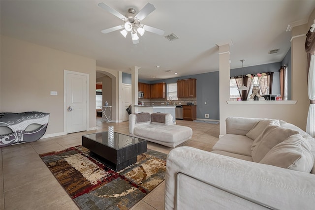 living room featuring visible vents, arched walkways, light tile patterned flooring, and a wealth of natural light