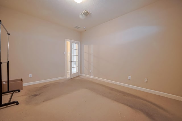 empty room featuring baseboards, visible vents, and light carpet