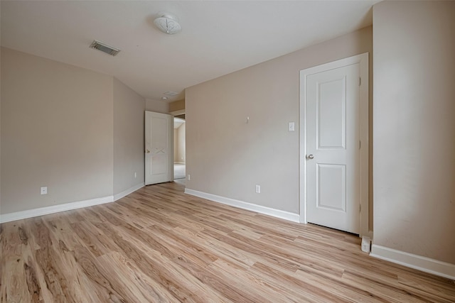unfurnished room featuring baseboards, light wood finished floors, and visible vents