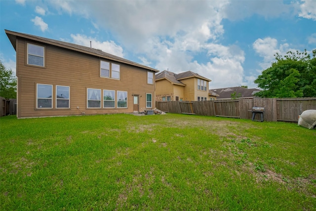back of property with a fenced backyard and a yard