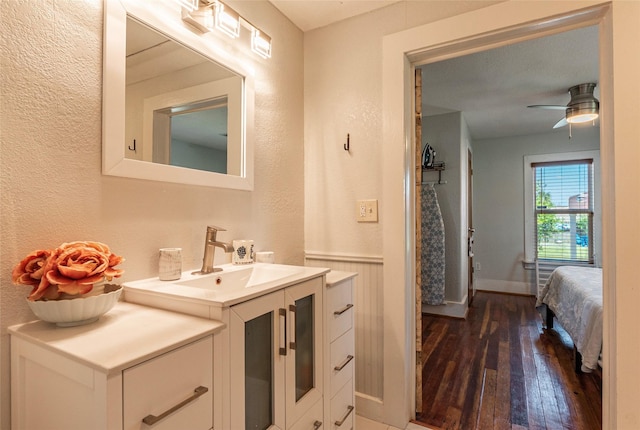 2216 Grover Ave, Galveston, TX 77551 - bathroom with hardwood / wood-style floors, ceiling fan, vanity, a textured wall, and baseboards
