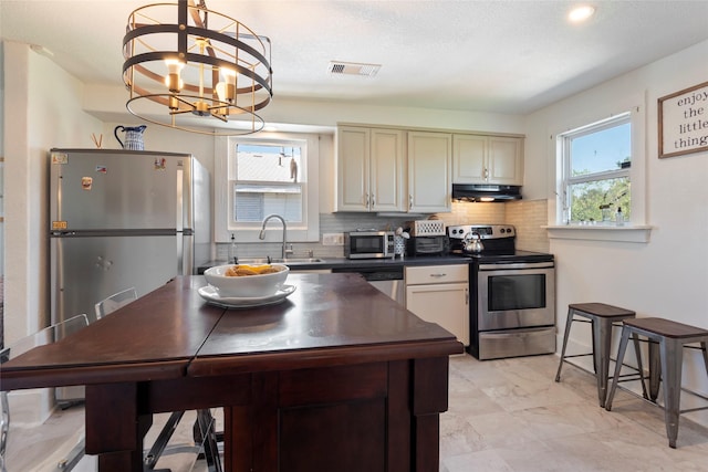 2216 Grover Ave, Galveston, TX 77551 - kitchen with appliances with stainless steel finishes, dark countertops, extractor fan, a sink, and tasteful backsplash