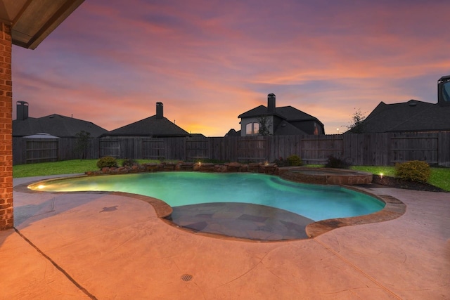 pool at dusk with a patio area, a pool with connected hot tub, and a fenced backyard