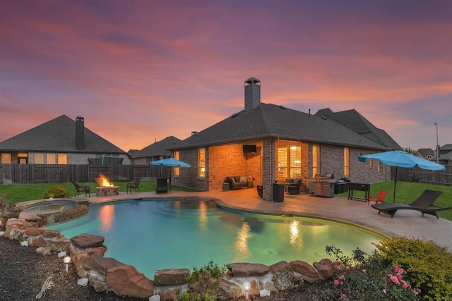 view of swimming pool featuring a fenced backyard, an outdoor fire pit, a pool with connected hot tub, and a patio