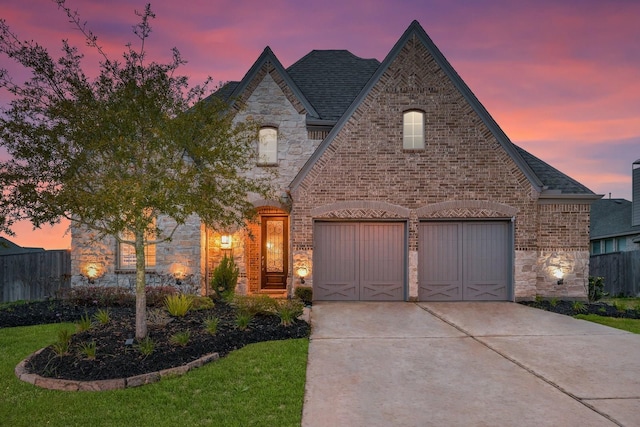 french country inspired facade with brick siding, driveway, stone siding, and fence