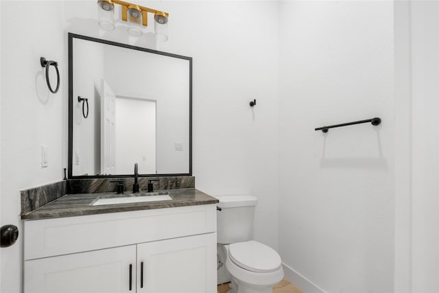 bathroom with toilet, vanity, and baseboards