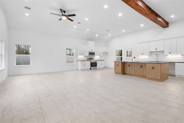 kitchen featuring visible vents, open floor plan, ceiling fan, appliances with stainless steel finishes, and decorative backsplash