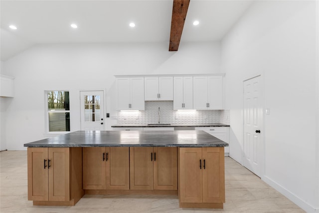kitchen featuring tasteful backsplash, white cabinetry, a spacious island, and dark countertops
