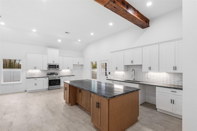 kitchen with a center island, white cabinets, a sink, beam ceiling, and stainless steel appliances