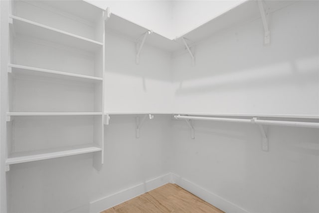 walk in closet with light wood-style floors