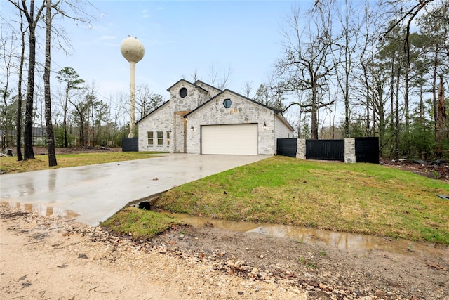 view of home's exterior with a yard, fence, stone siding, an attached garage, and driveway