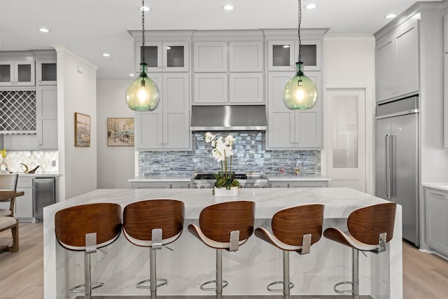 11370 Beachside, Galveston, TX 77554 - kitchen featuring a breakfast bar, range, glass insert cabinets, built in fridge, and under cabinet range hood
