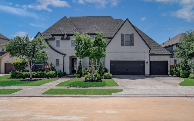 french provincial home with an attached garage, roof with shingles, driveway, and stucco siding