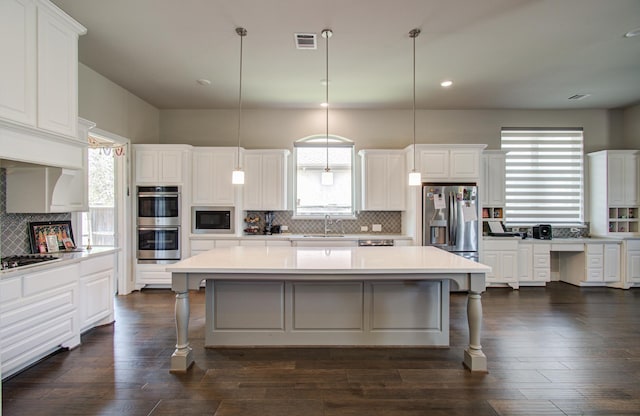 kitchen featuring tasteful backsplash, visible vents, a center island, a sink, and stainless steel appliances