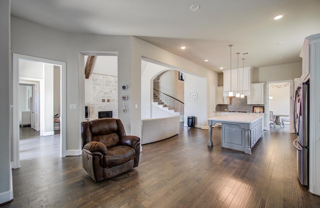 kitchen featuring a fireplace, a kitchen breakfast bar, dark wood-style flooring, light countertops, and open floor plan