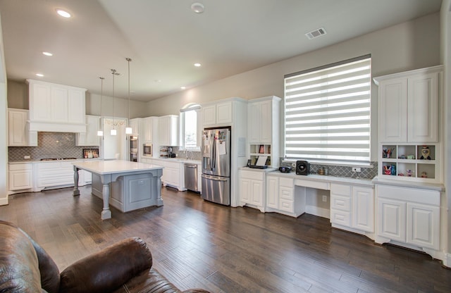 kitchen featuring visible vents, appliances with stainless steel finishes, a kitchen breakfast bar, white cabinetry, and built in study area