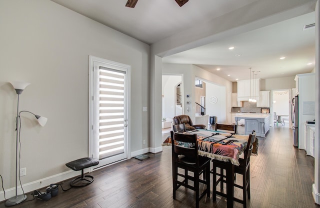 dining space with dark wood-type flooring, visible vents, baseboards, and a ceiling fan