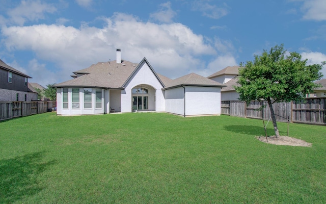 back of house with a fenced backyard, a lawn, and a chimney