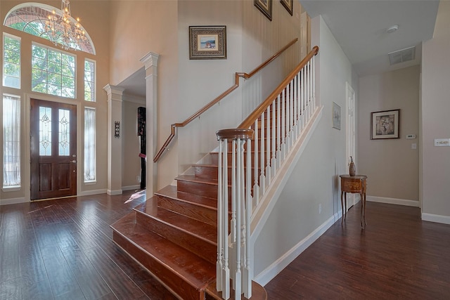 entrance foyer featuring visible vents, a chandelier, a high ceiling, stairs, and dark wood-style floors