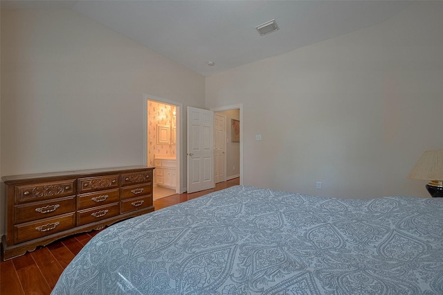 bedroom with dark wood-type flooring, visible vents, ensuite bath, and lofted ceiling