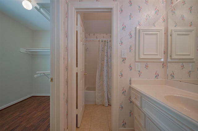 full bathroom featuring vanity, tile patterned flooring, wallpapered walls, shower / bath combo with shower curtain, and baseboards