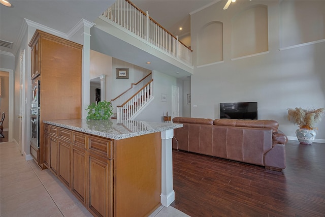 kitchen with open floor plan, appliances with stainless steel finishes, light wood-style floors, brown cabinets, and crown molding
