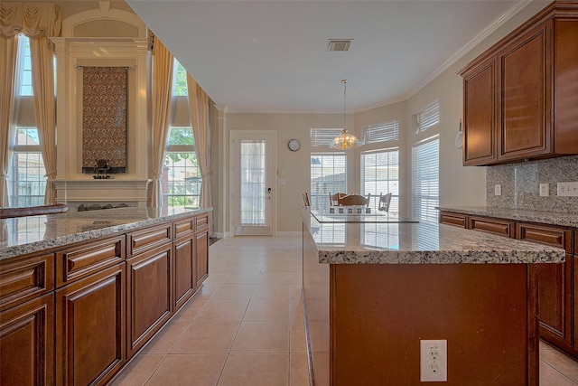 kitchen featuring tasteful backsplash, visible vents, a center island, baseboards, and a notable chandelier