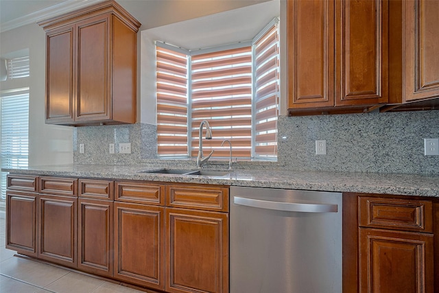 kitchen featuring tasteful backsplash, light stone counters, brown cabinets, dishwasher, and a sink