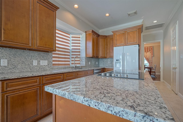 kitchen featuring brown cabinetry, white refrigerator with ice dispenser, a sink, and visible vents