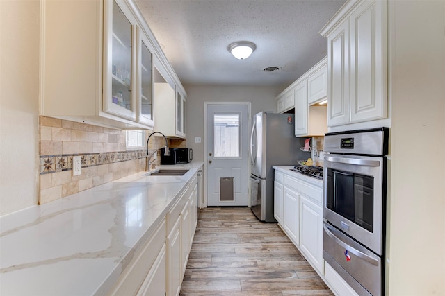 4103 Donna Lynn Dr, Houston, TX 77092 - kitchen featuring tasteful backsplash, a sink, light wood-type flooring, a warming drawer, and stainless steel appliances