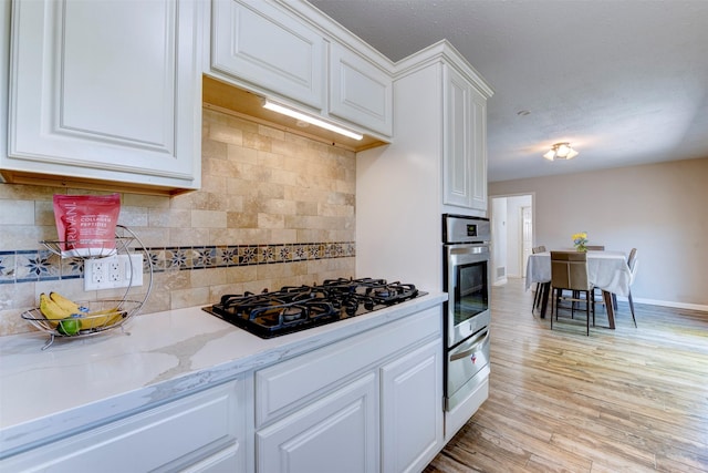 4103 Donna Lynn Dr, Houston, TX 77092 - kitchen featuring light wood-style flooring, white cabinets, black gas stovetop, oven, and baseboards