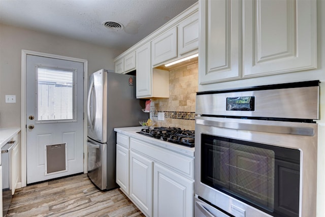 4103 Donna Lynn Dr, Houston, TX 77092 - kitchen featuring visible vents, light countertops, appliances with stainless steel finishes, white cabinetry, and light wood finished floors
