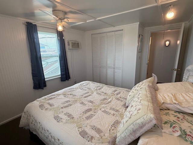 bedroom with ceiling fan, a closet, attic access, and an AC wall unit