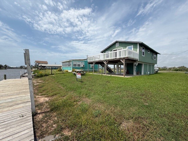 rear view of house with a lawn, a deck, and stairs