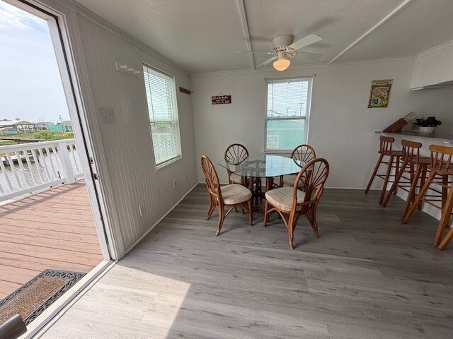 dining room featuring light wood-style floors, ornamental molding, baseboards, and a ceiling fan