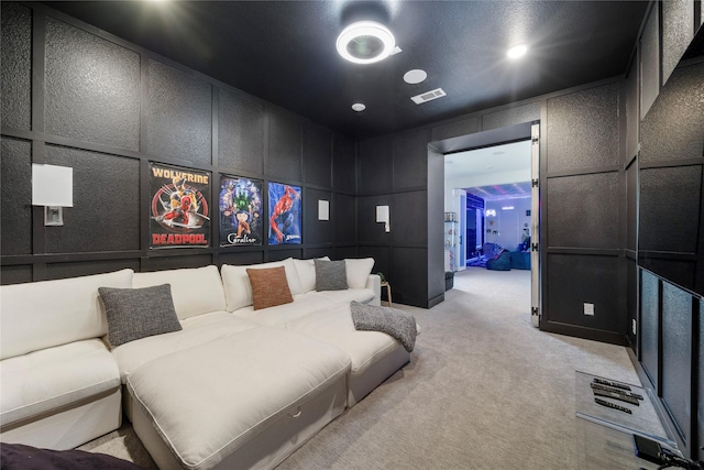 home theater featuring a decorative wall, light colored carpet, and visible vents