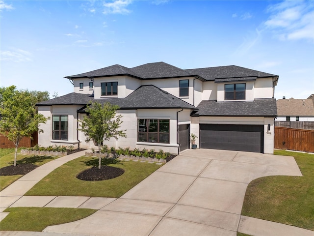 prairie-style house featuring a garage, stucco siding, fence, a front lawn, and driveway