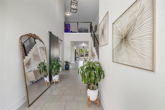 hallway featuring baseboards, a high ceiling, and stairs