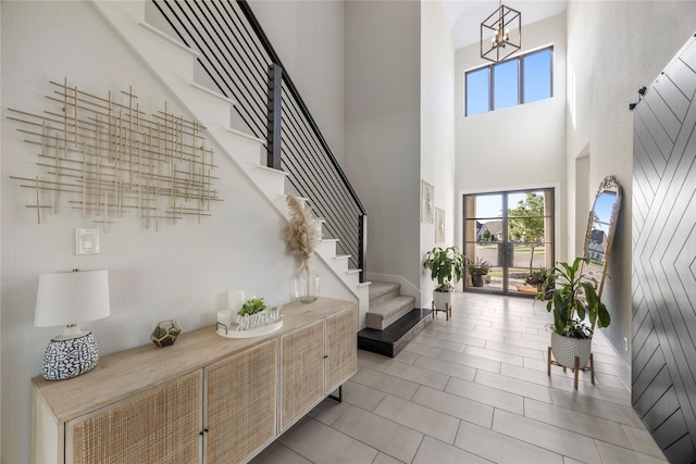 entryway featuring a chandelier, light tile patterned floors, a towering ceiling, and stairs