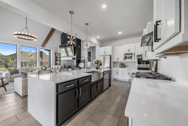 kitchen featuring a sink, open floor plan, appliances with stainless steel finishes, and white cabinetry