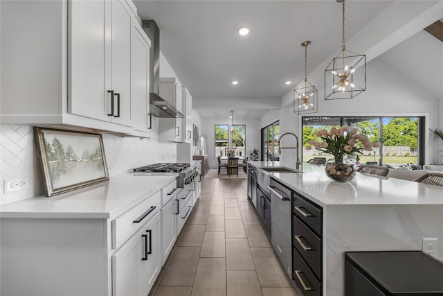 kitchen featuring wall chimney range hood, a large island with sink, and white cabinets