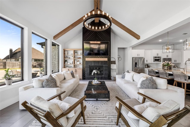 living room featuring baseboards, an inviting chandelier, a fireplace, and beam ceiling