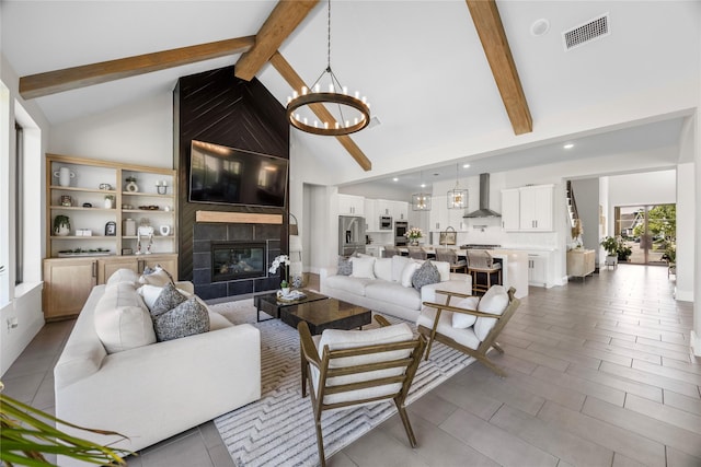 living area featuring a large fireplace, visible vents, a notable chandelier, and beamed ceiling