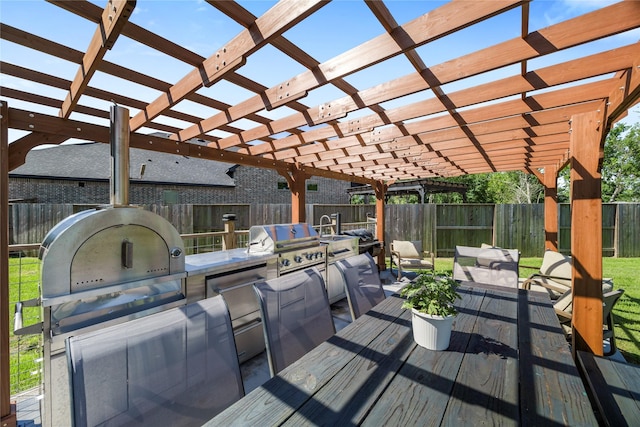wooden deck with a pergola, exterior kitchen, fence, and area for grilling